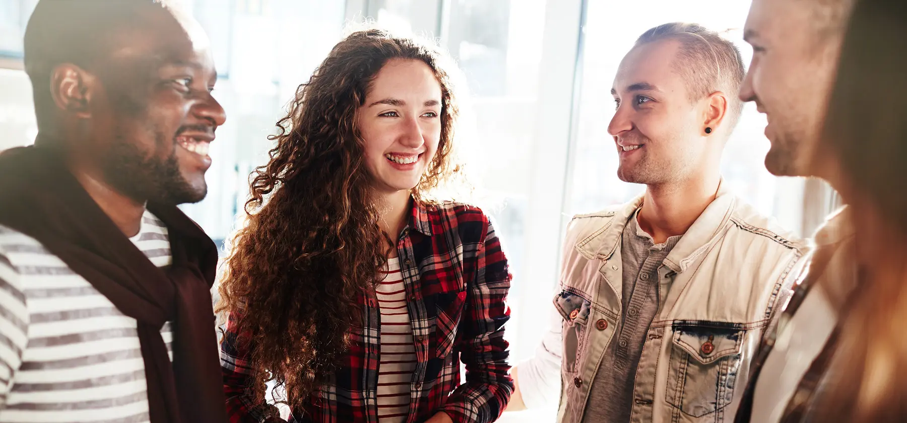 Foto de quatro pessoas em pé, olhando e sorrindo entre si.