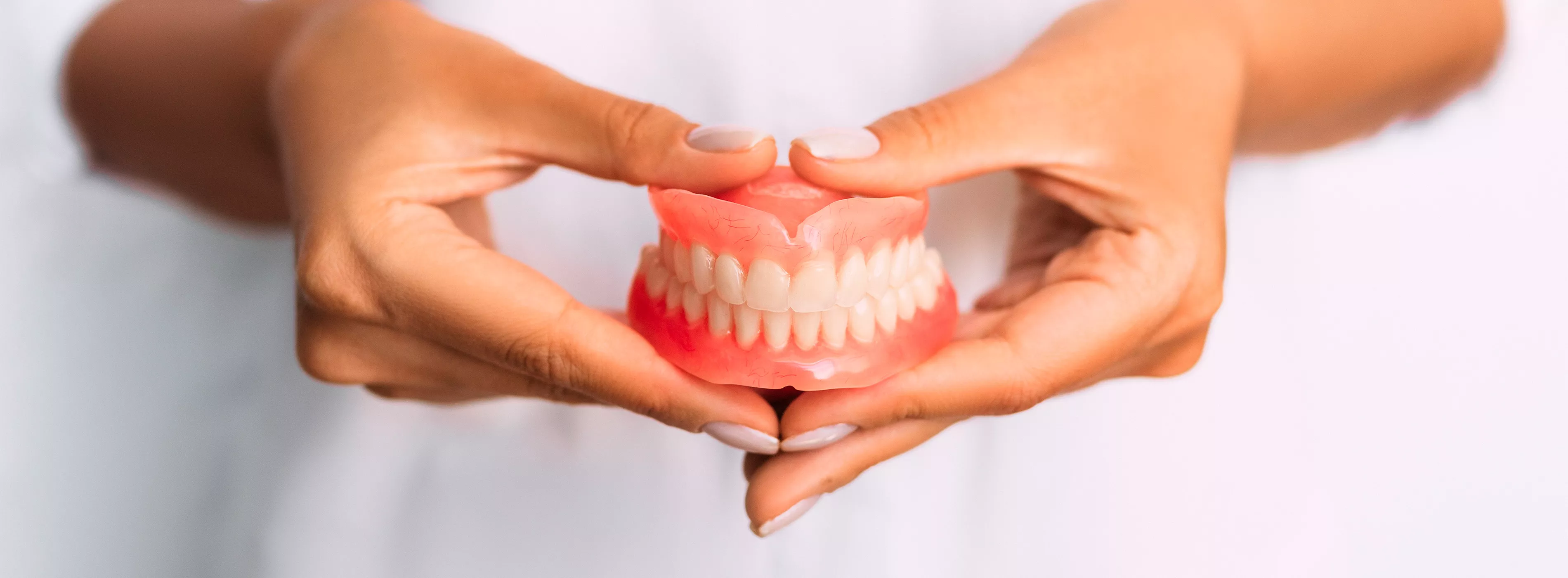 Foto em close de duas mãos segurança um molde de uma arcada dentária.