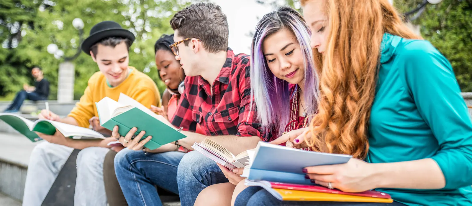 Foto de grupo de adolescentes sentados estudando livros