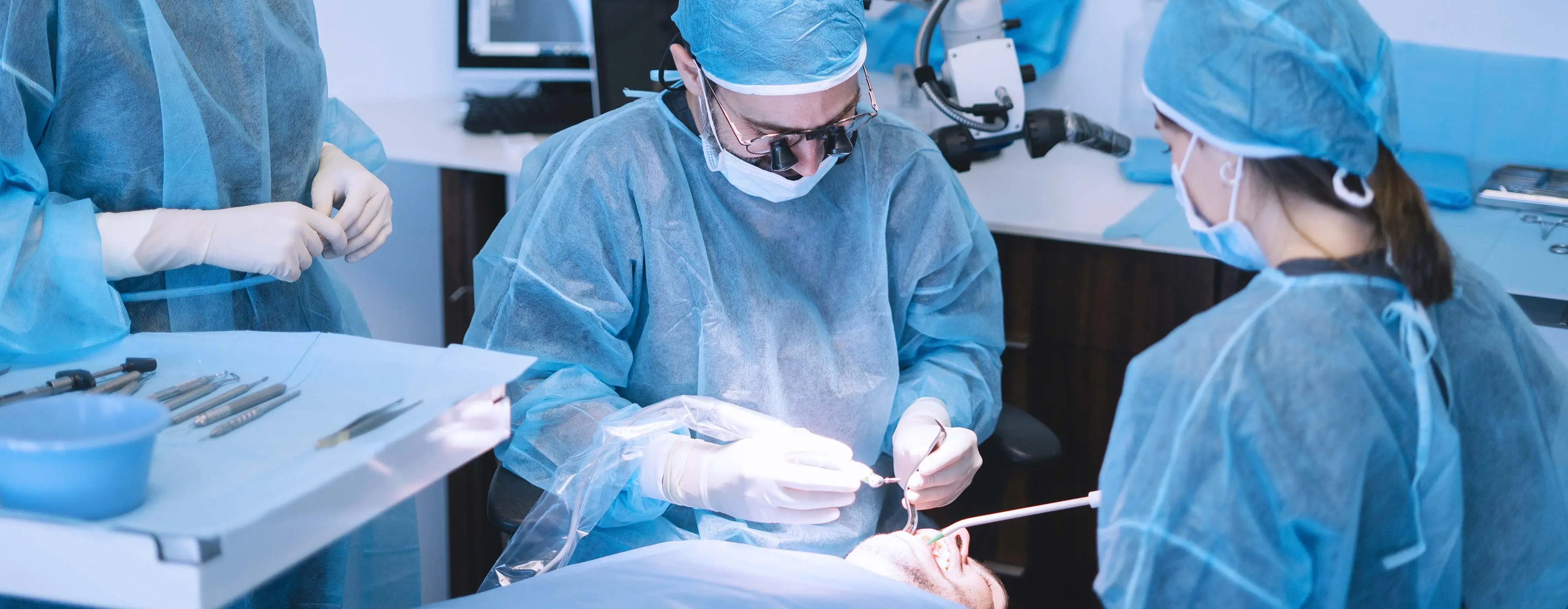 Foto de cirurgião-dentista e profissionais de saúde realizando cirurgia paraendodôntica.