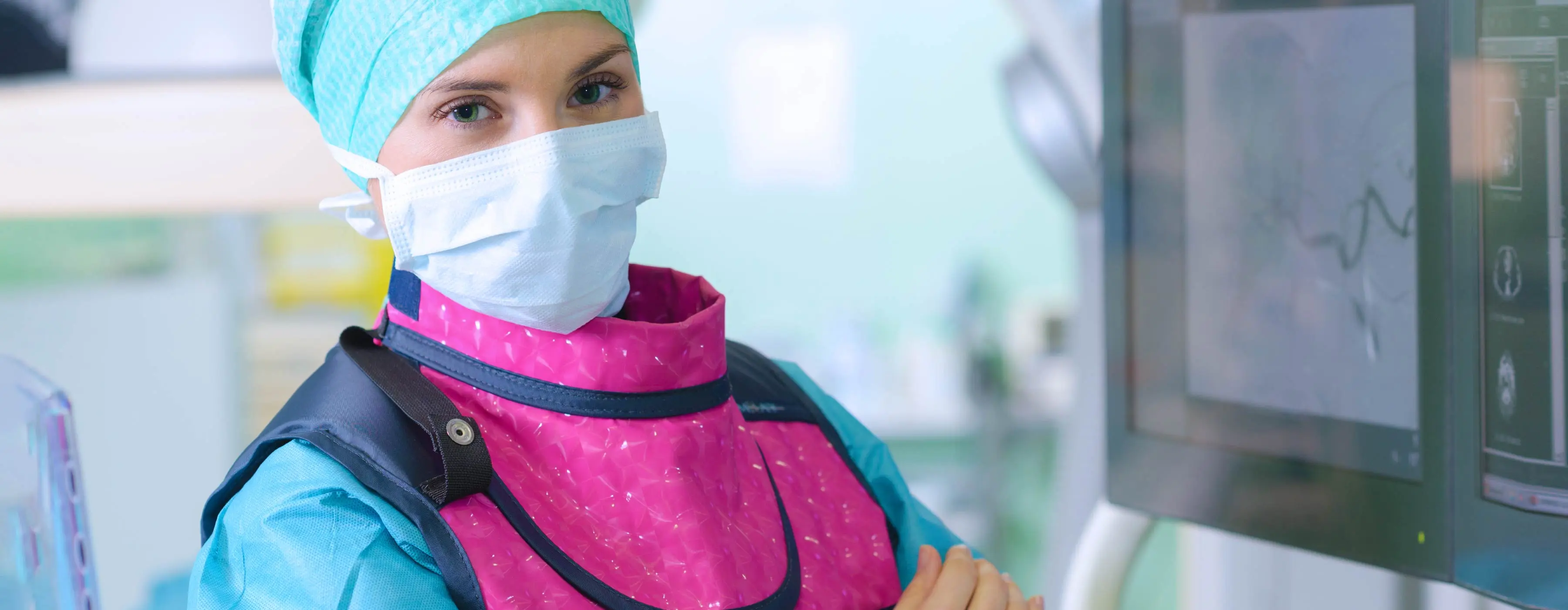Foto em close de uma profissional de saúde, com uniforme especial, realizando exame de imagem.