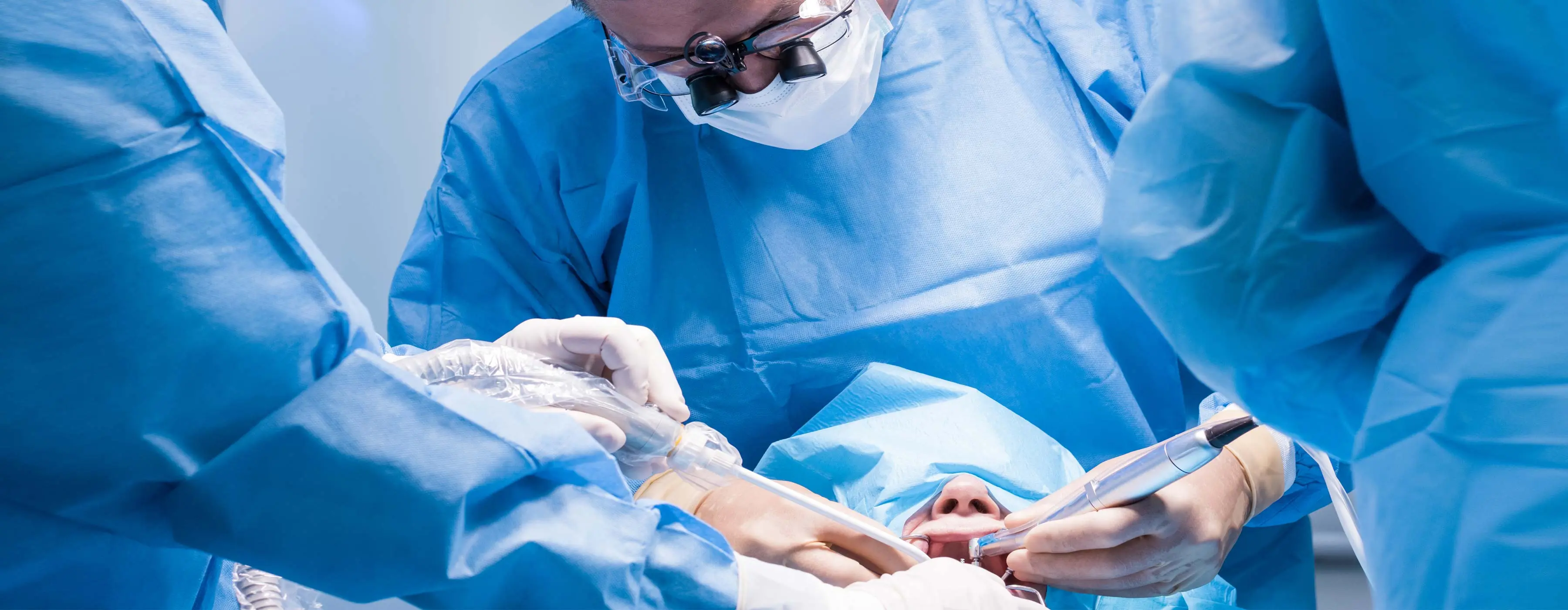 Foto em close de cirurgião-dentista e profissional de saúde realizando cirurgia.