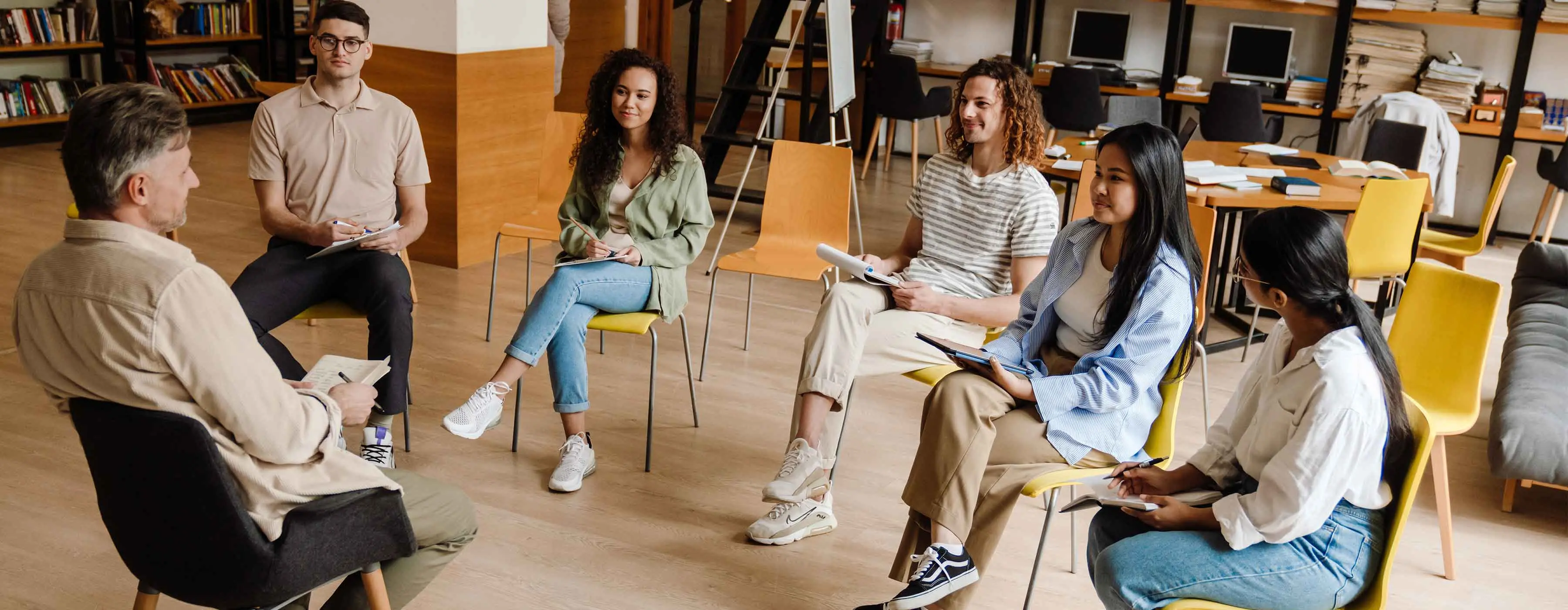 Foto de pessoas sentadas em roda em uma sala de aula