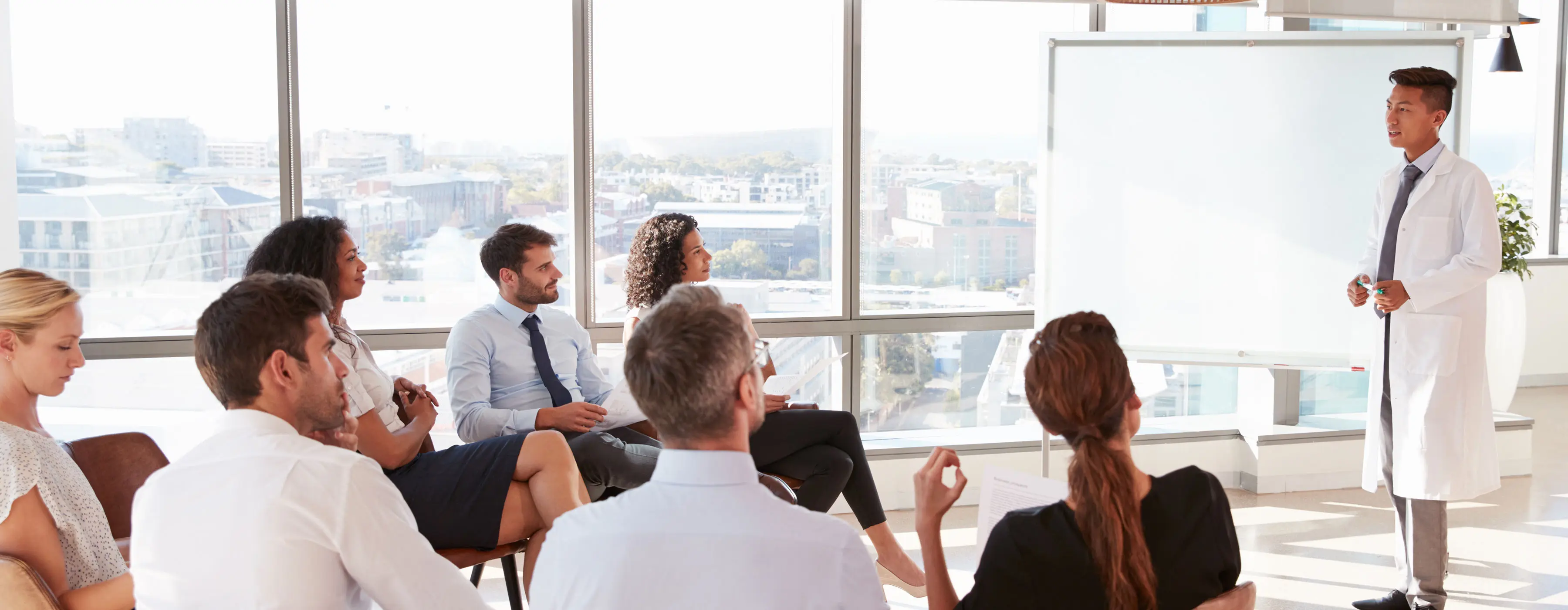 Foto de palestrante da área de saúde fazendo apresentação para um grupo de pessoas.