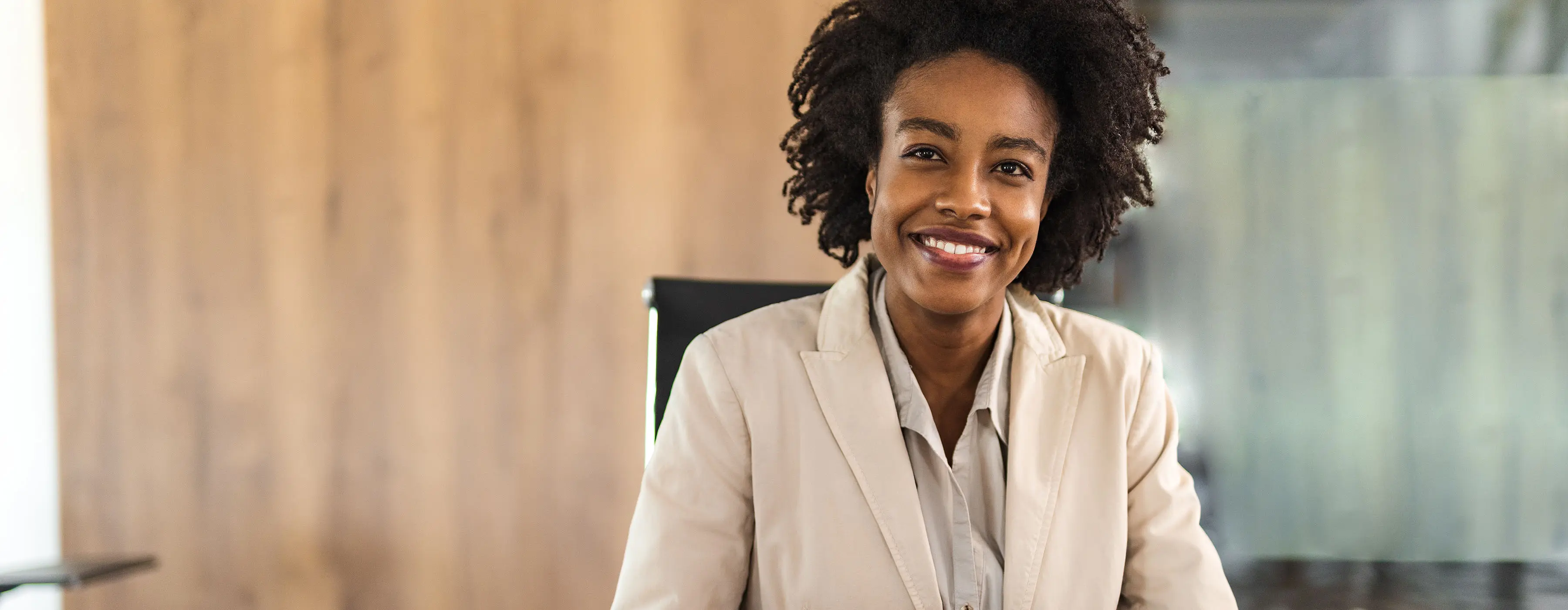 Foto de uma mulher negra sorrindo, em ambiente profissional.