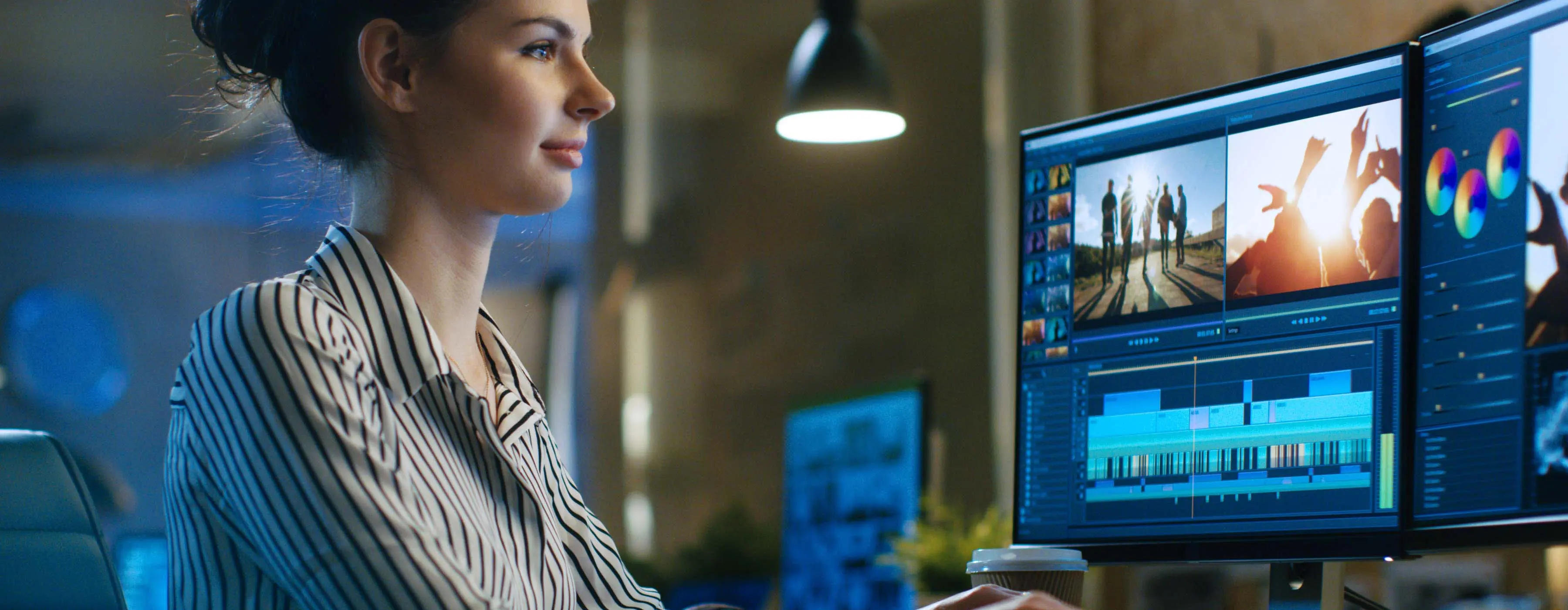 Foto de uma mulher jovem sentada de frente digitando no teclado e trabalhando com imagens na tela do computador.
