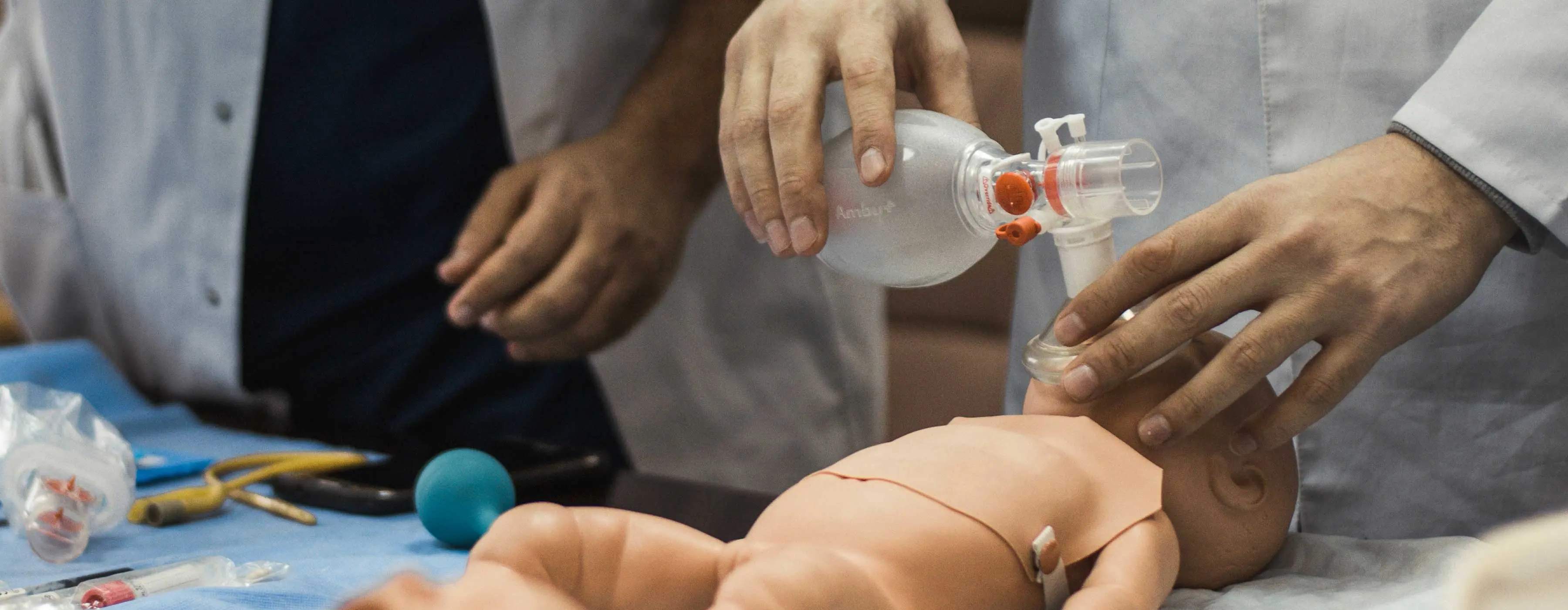 Foto em close das mãos de um profissional de saúde realizando procedimento em um boneco. bebê.