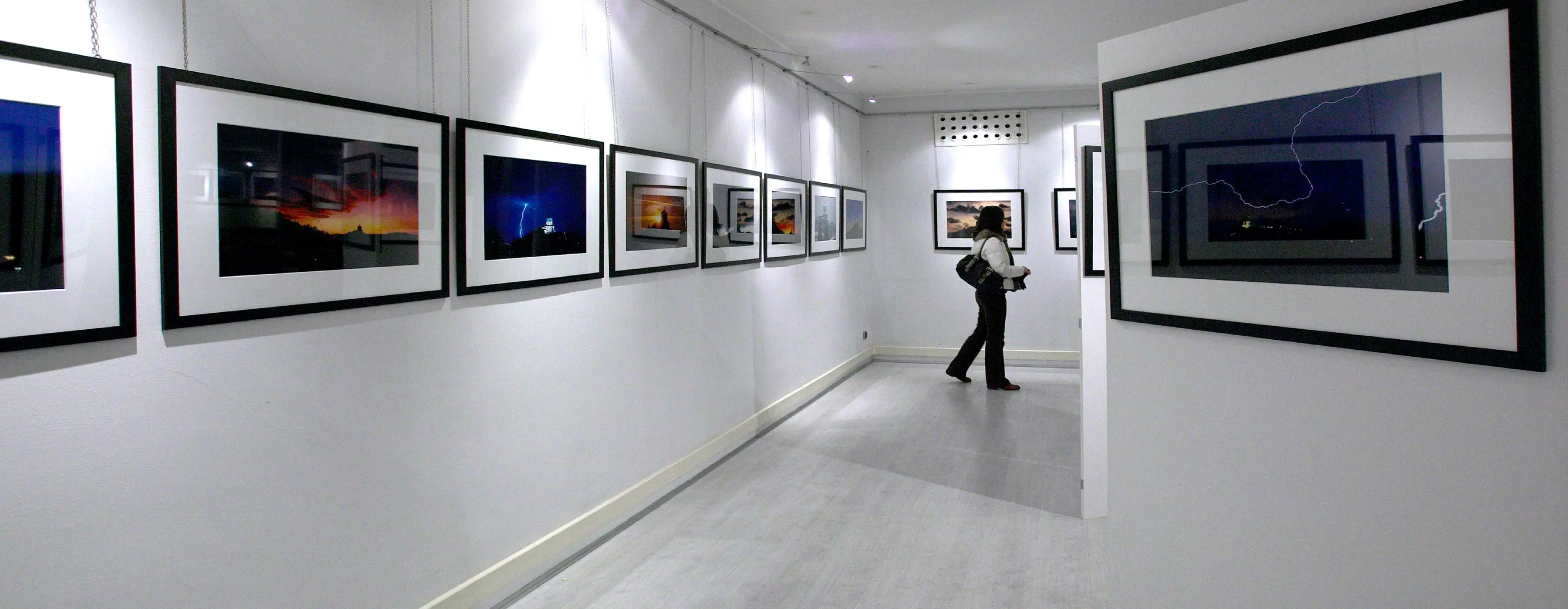 Foto de mulher observando uma exposição fotográfica.