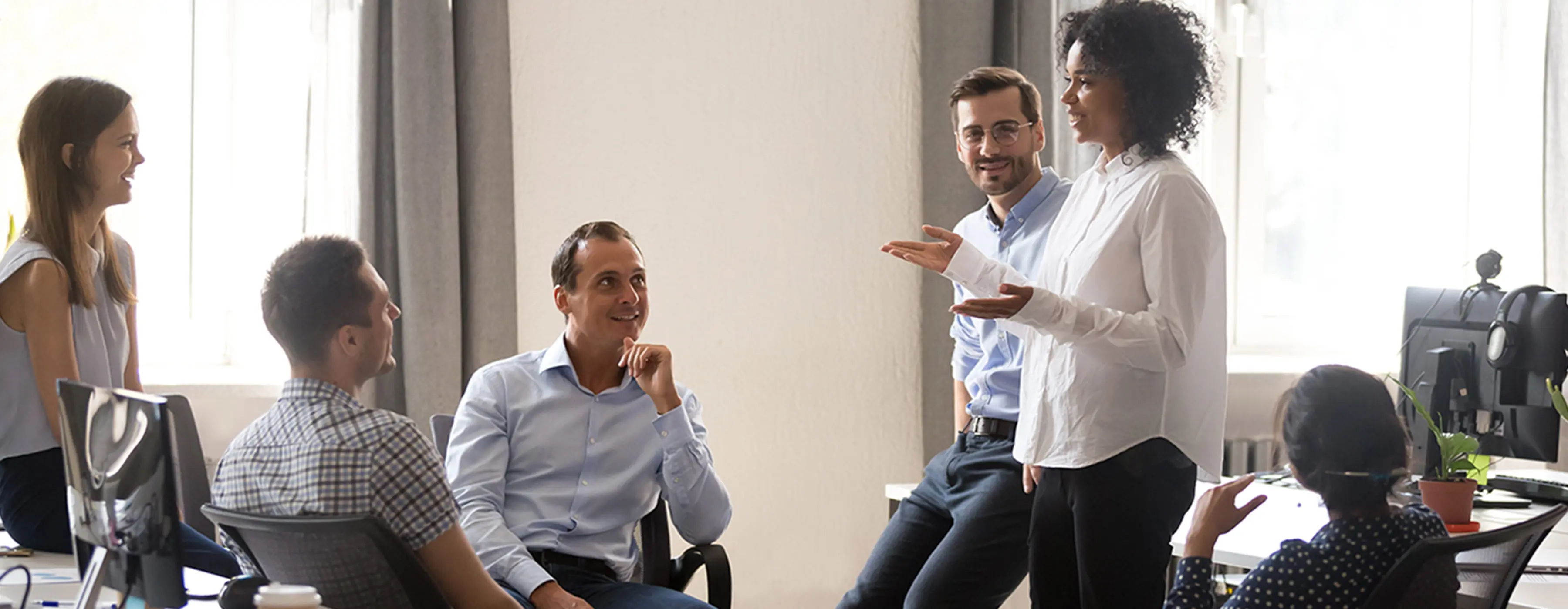 Foto de grupo de pessoas conversando em reunião em escritório, no centro mulher em pé falando.