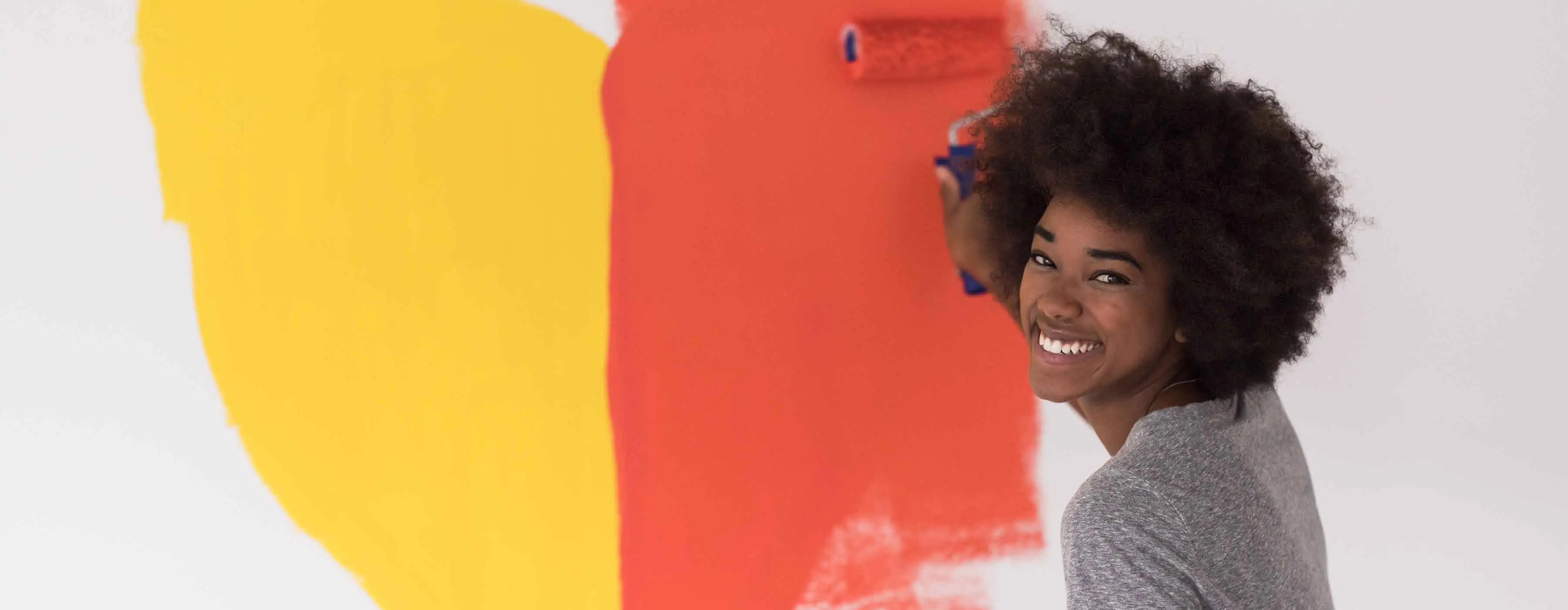 Foto de uma mulher pintando uma parede