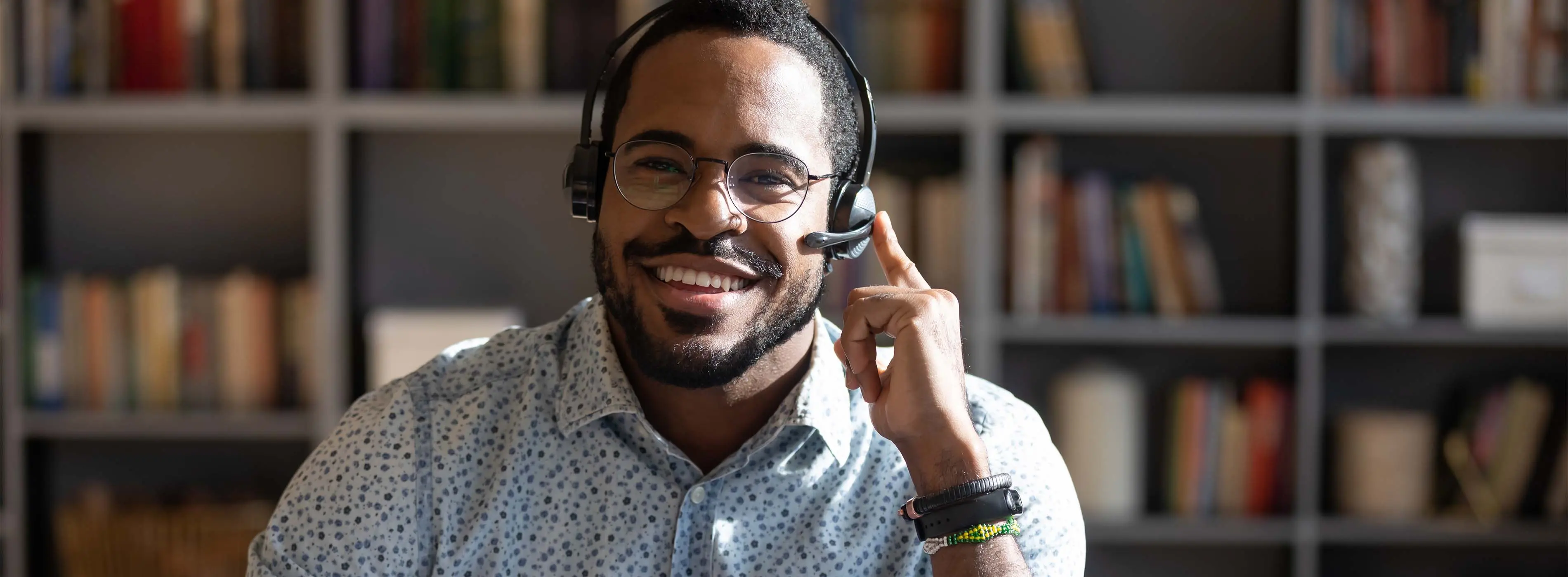 Foto de homem sorridente usando um fone que tem microfone