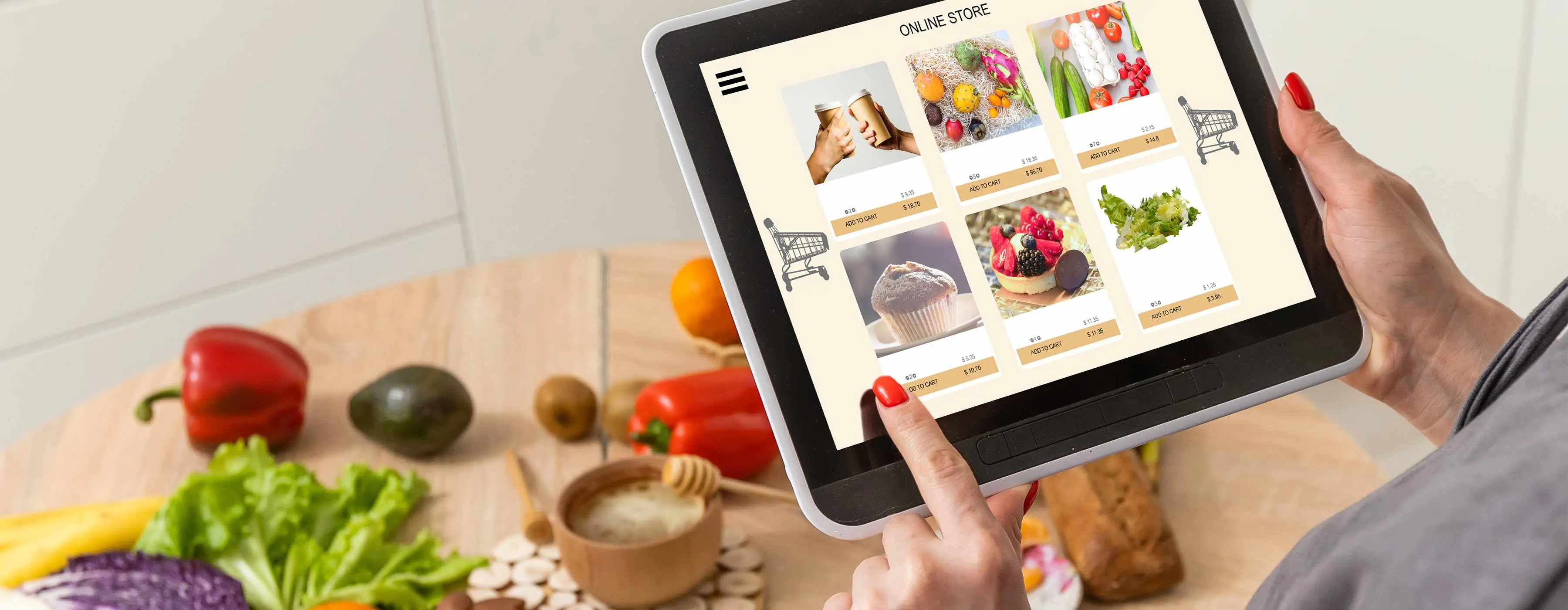 Foto de uma mesa com legumes e verduras e as mãos de uma pessoa segurando um tablet.