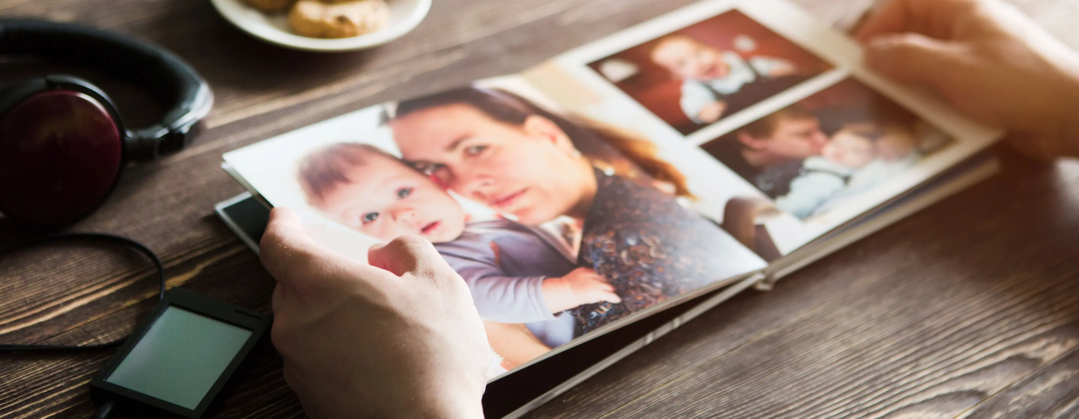 Foto em close de mãos manipulando um álbum de fotografias.