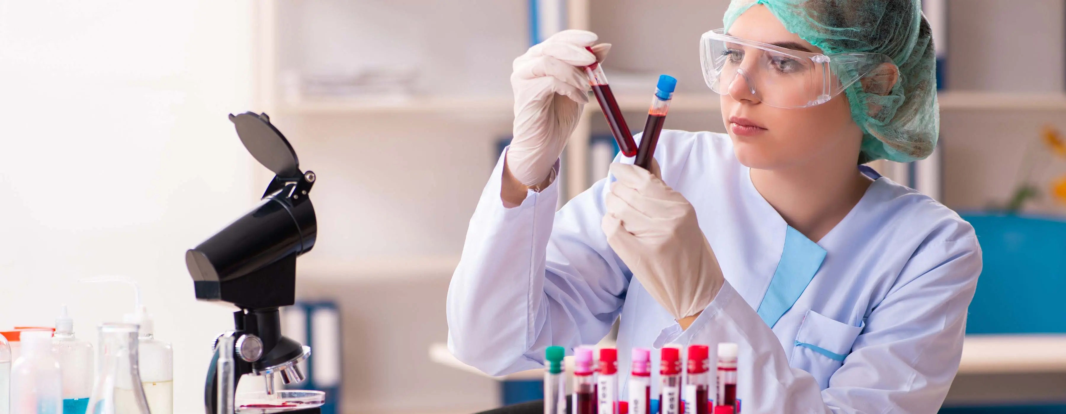 Foto de uma mulher observando tubo de sangue em laboratório.
