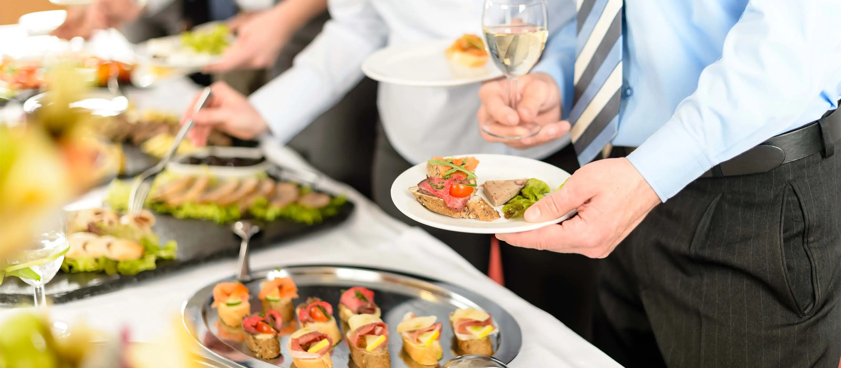 Foto de homem segurando um prato e montando sua refeição em um buffet.