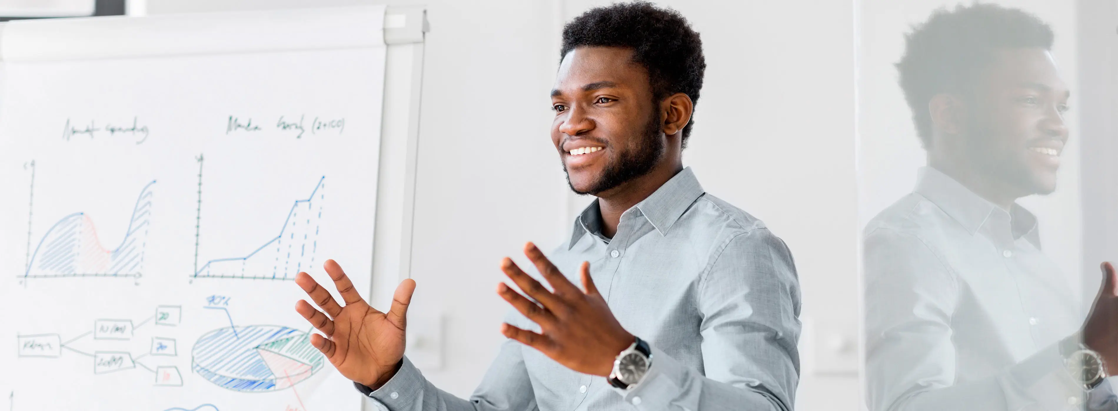 Foto em close de um homem negro em ambiente corporativo fazendo uma apresentação.
