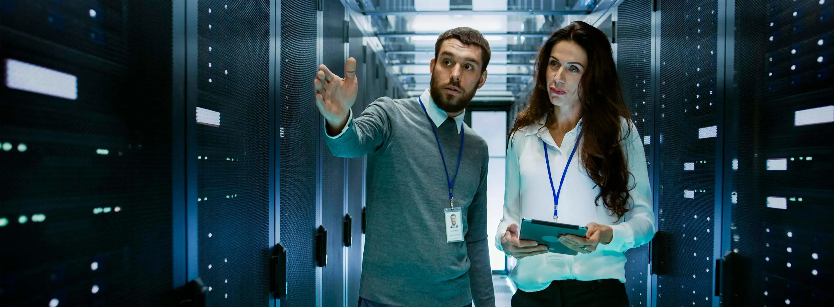 Foto de um homem mostrando para uma mulher um ambiente de máquinas virtuais, servidores de uma empresa.