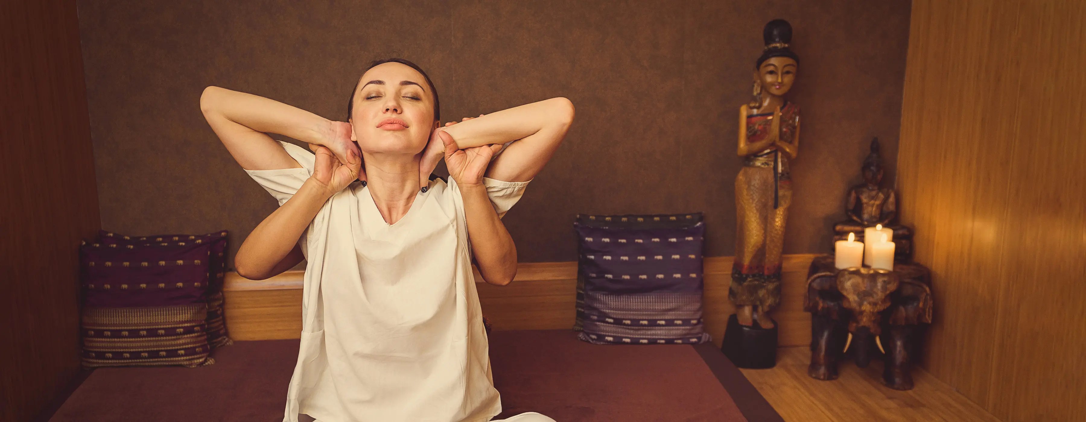 Foto de mulher recebendo massagem na cervical em sala de massagem com decoração oriental.