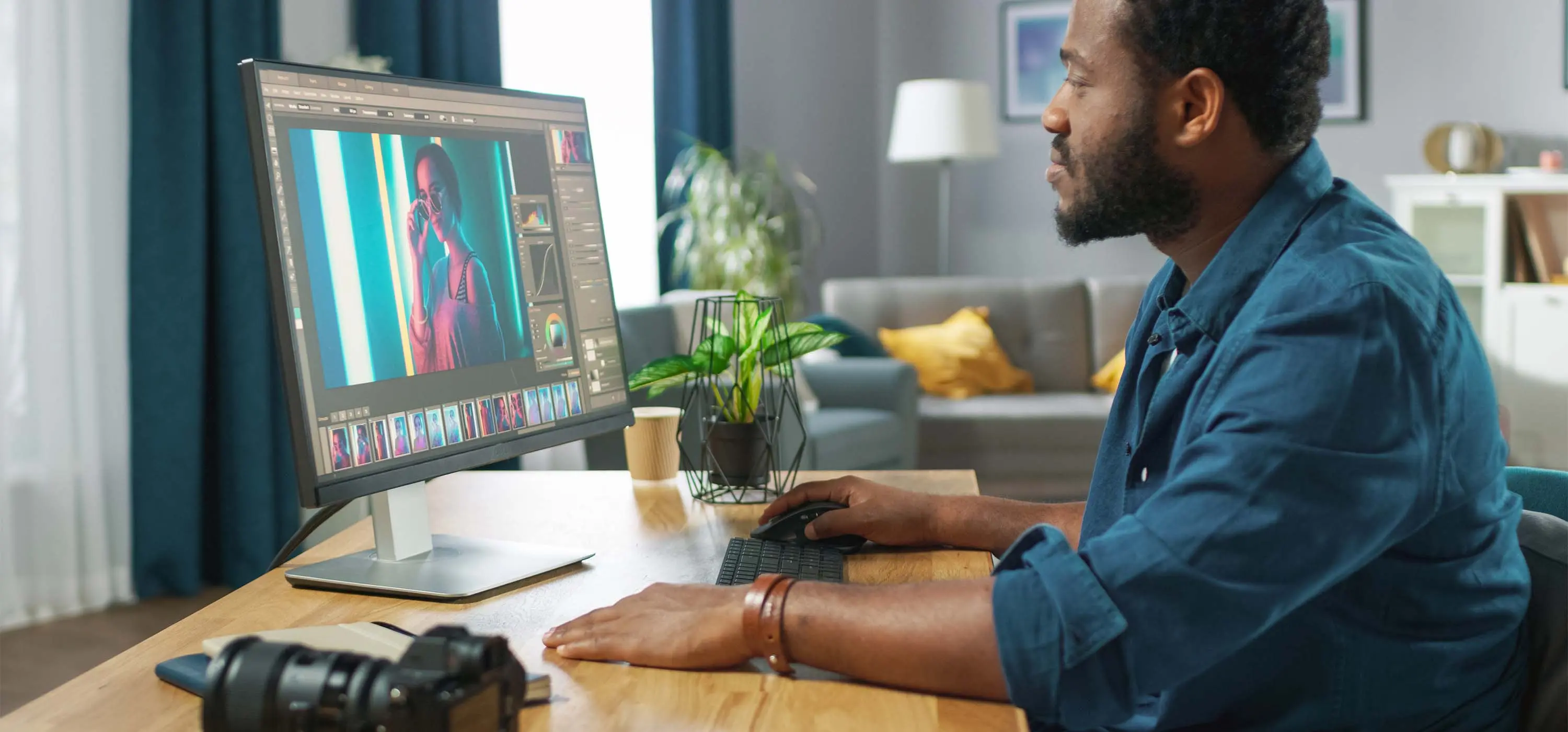 Foto de um homem sentado em frente a um computador fazendo tratamento de imagem.