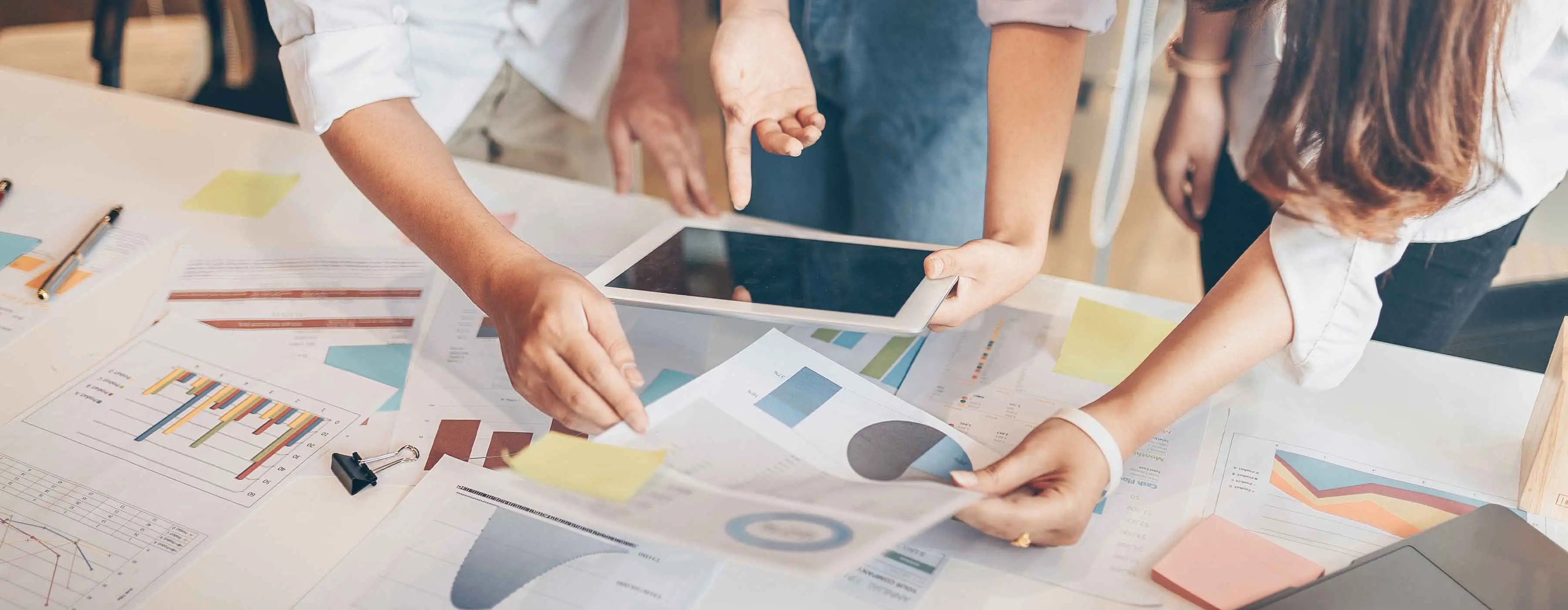 Profissionais observam gráficos em papéis sobre a mesa.