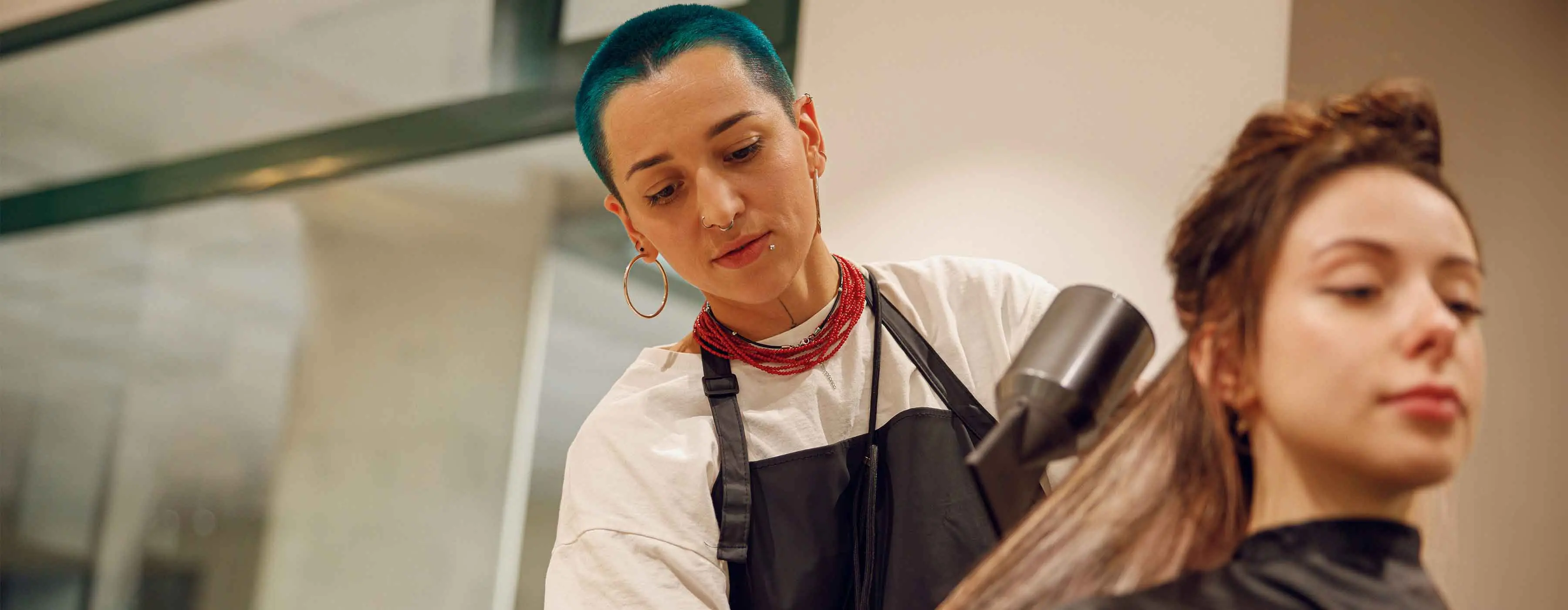 Foto de uma cabelereira secando o cabelo de uma cliente.
