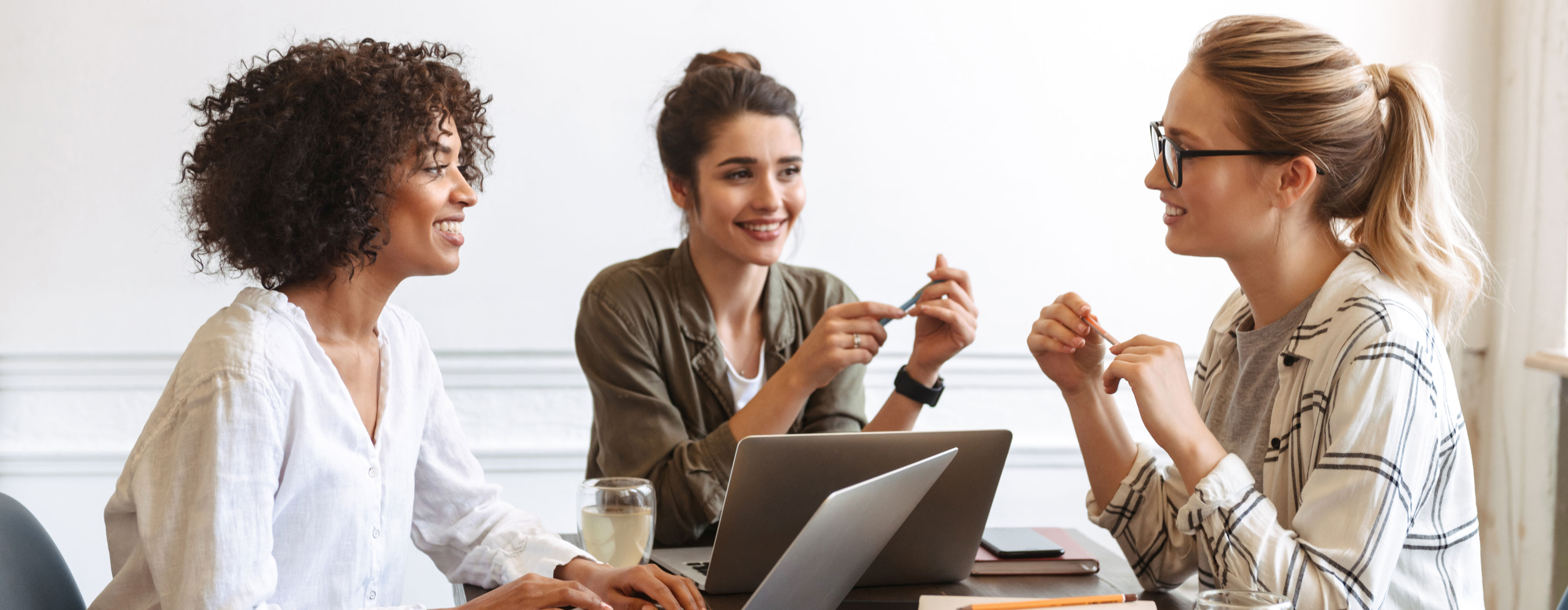Gestão Tributária: planejamento tributário - Foto de três mulheres sentadas, conversando em ambiente corporativo.