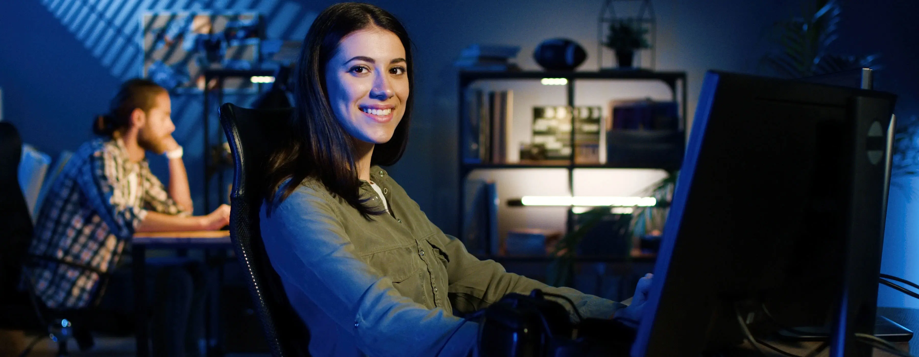 Foto de uma mulher editando vídeo em computador com dois monitores em estúdio.