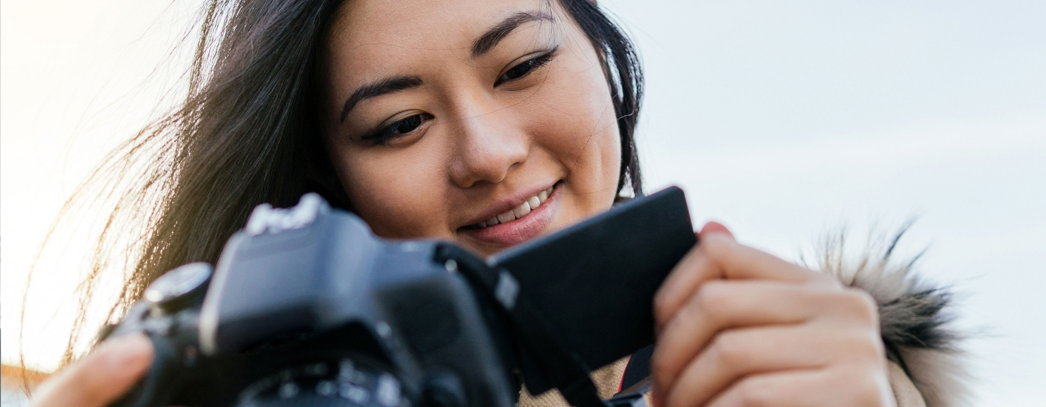 Foto de uma mulher olhando para uma máquina fotográfica e sorrindo.