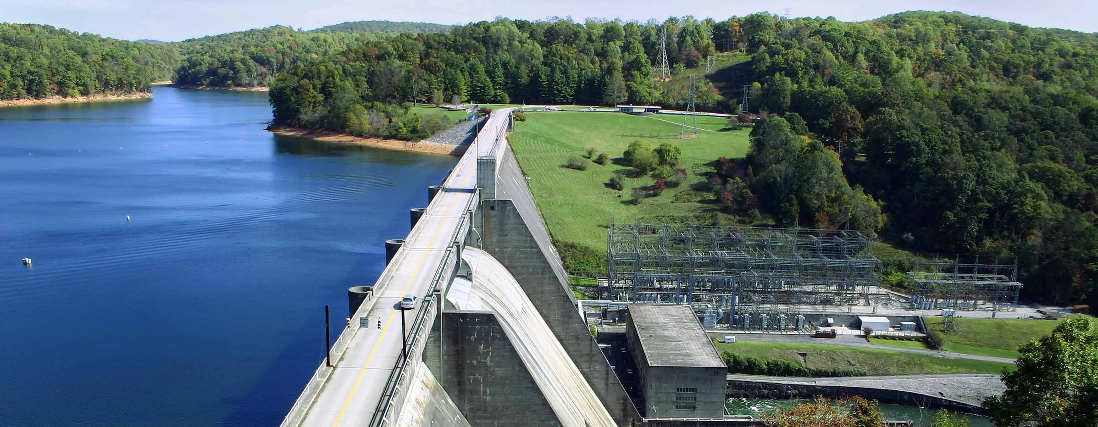 Foto de barragem e usina hidrelétrica com árvores ao redor.