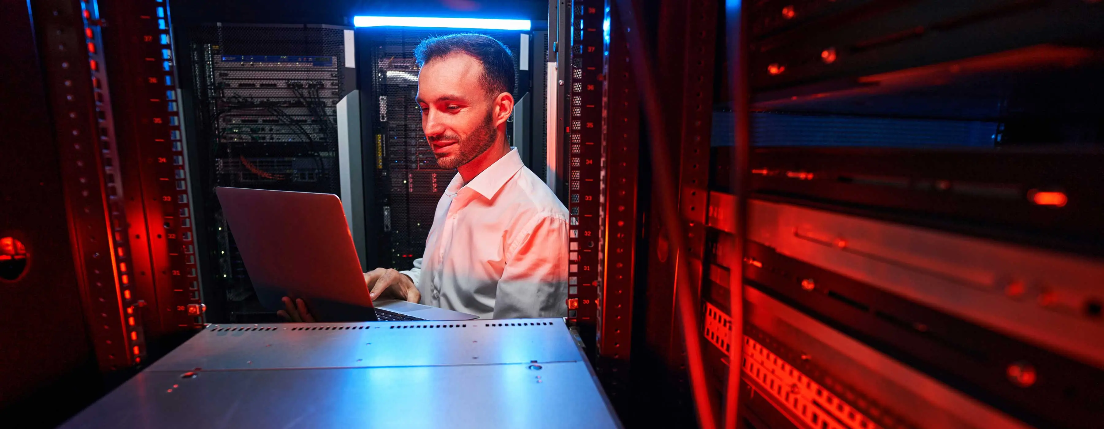 Foto de homem usando notebook em espaço de datacenter.