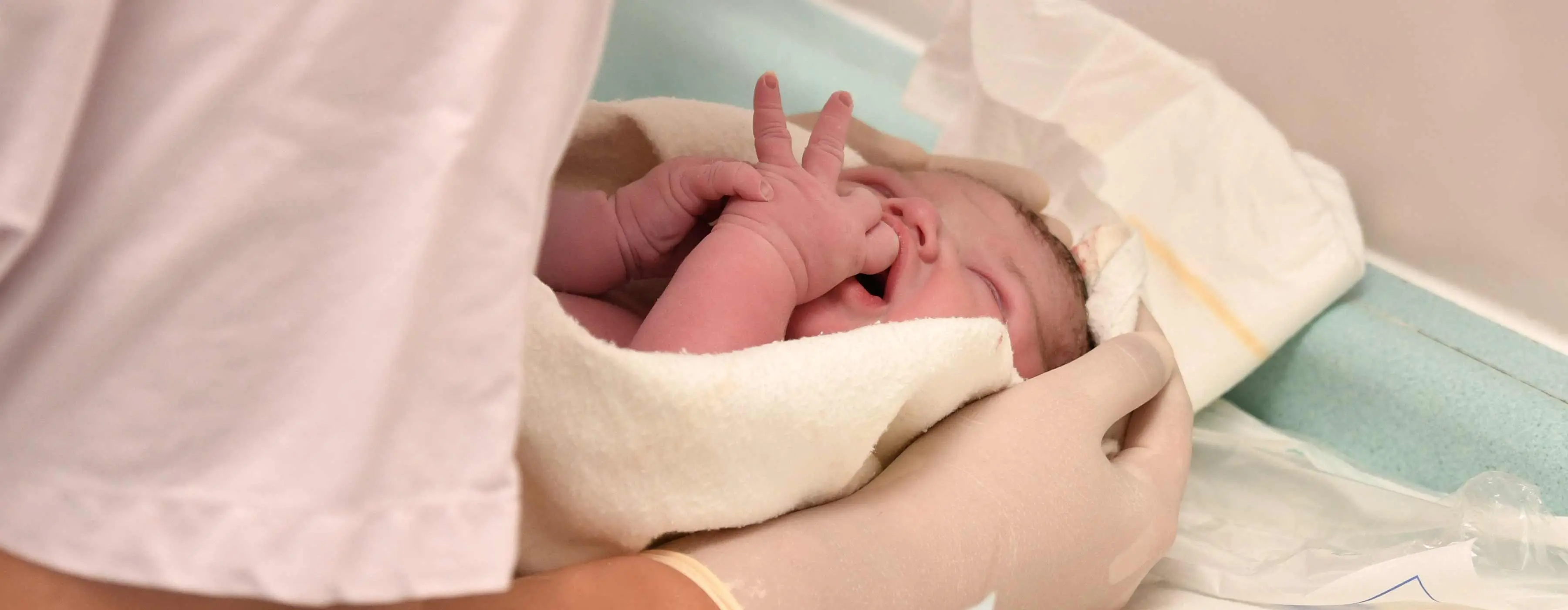 Foto de enfermeira cuidando do bebê recém-nascido após o parto.
