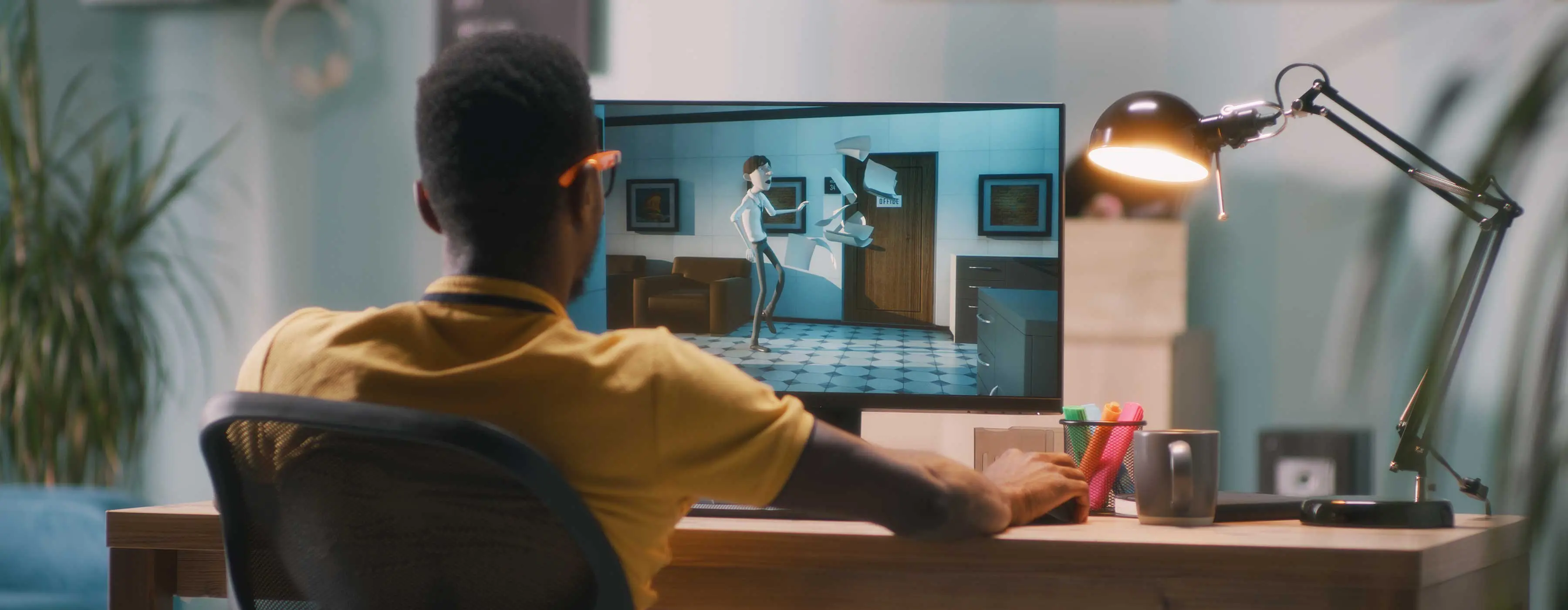 Foto de homem de costas, mexendo em um computador que apresenta uma animação gráfica.