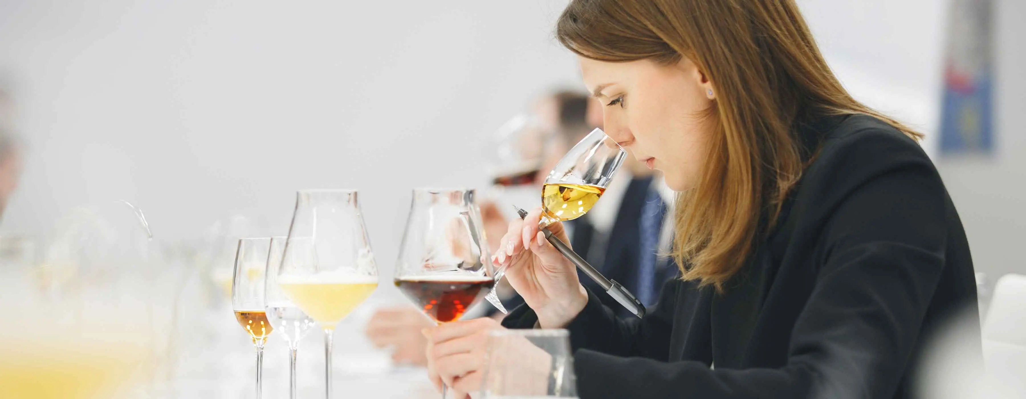 Foto de uma mulher sentindo o cheiro de um vinho em uma taça