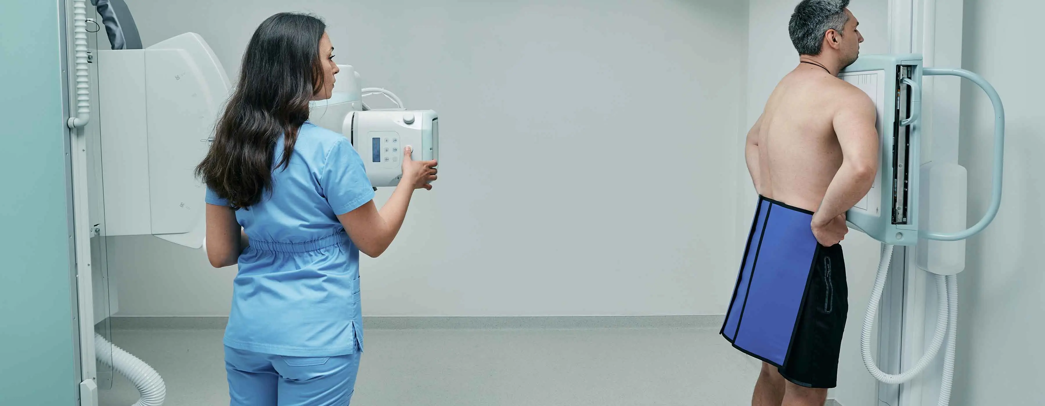 Foto de uma profissional de saúde operando uma máquina de raio-X em um paciente.