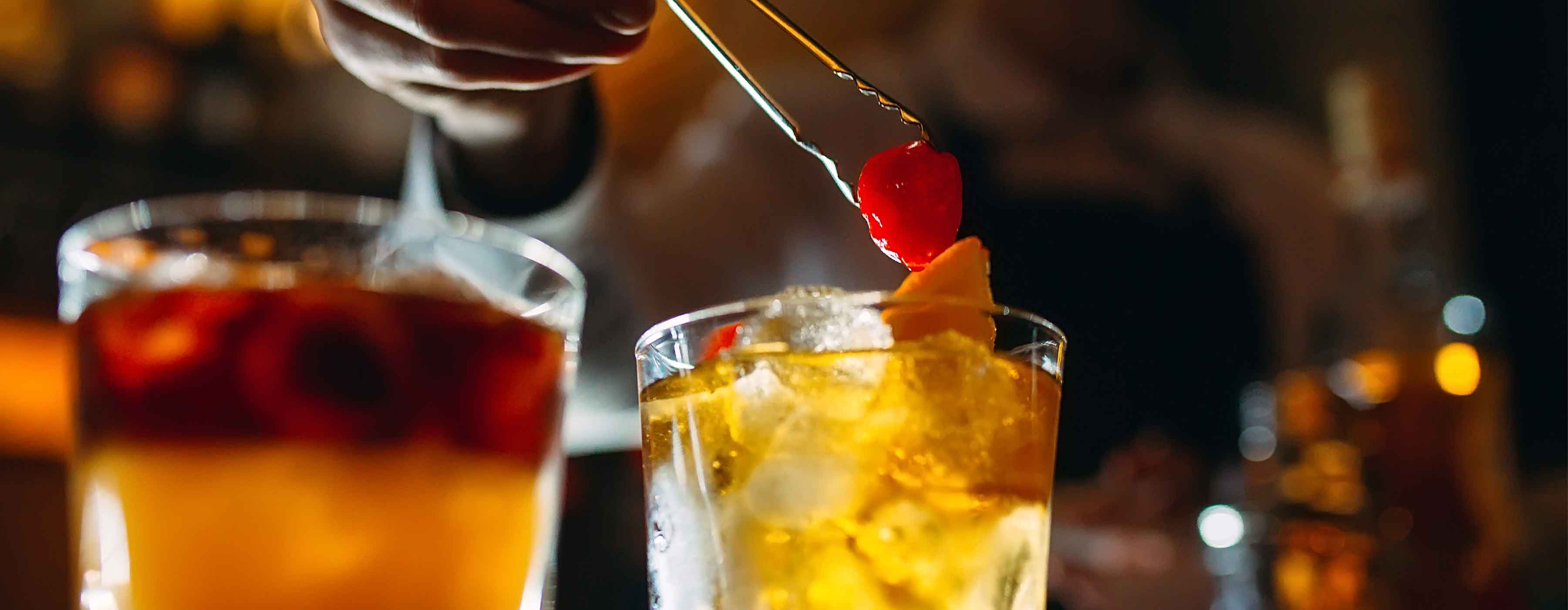 Bartender: decorações, guarnições e toppings para coquetéis ¿  foto de dois coquetéis nas cores amarelo e vermelho; um deles finalizado com uma cereja vermelha