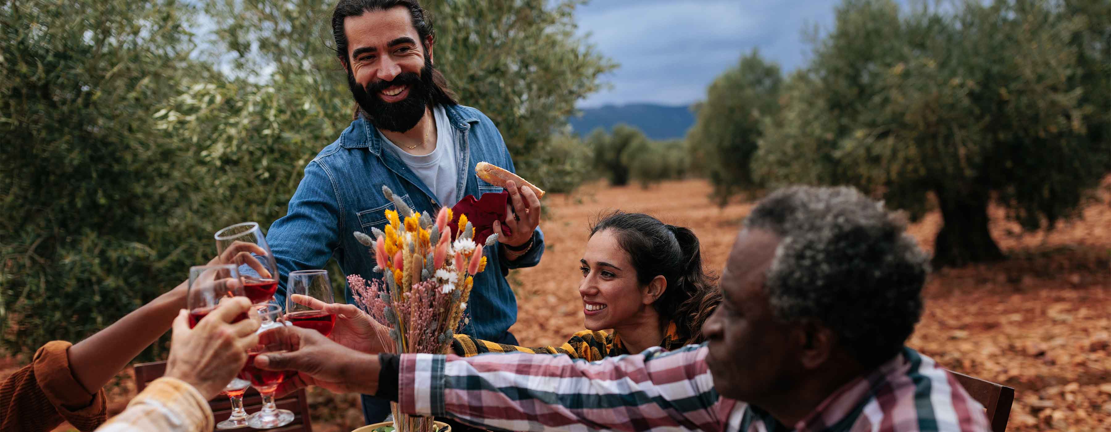Turismo Gastronômico: cultura, roteiros e experiências - foto de pessoas brindando com taças de bebida em ambiente de plantação.