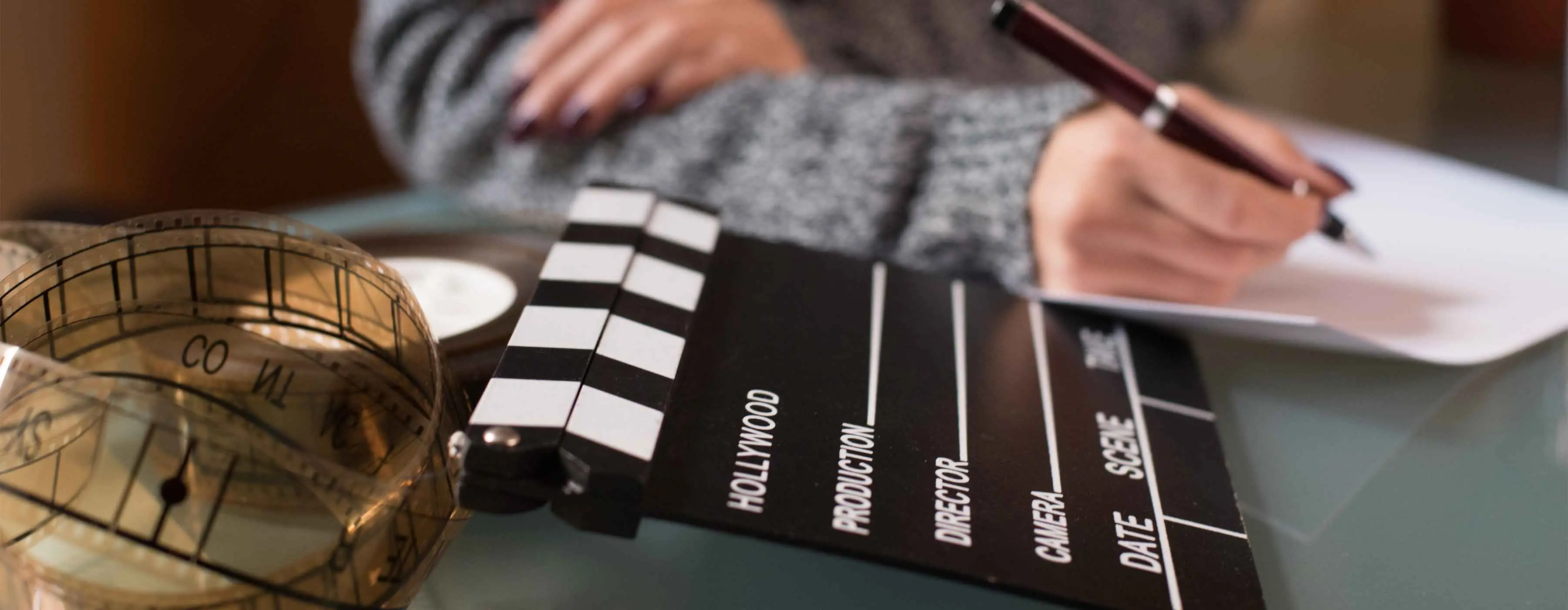 Imagem de uma claquete e um rolo de filme em cima de uma mesa.