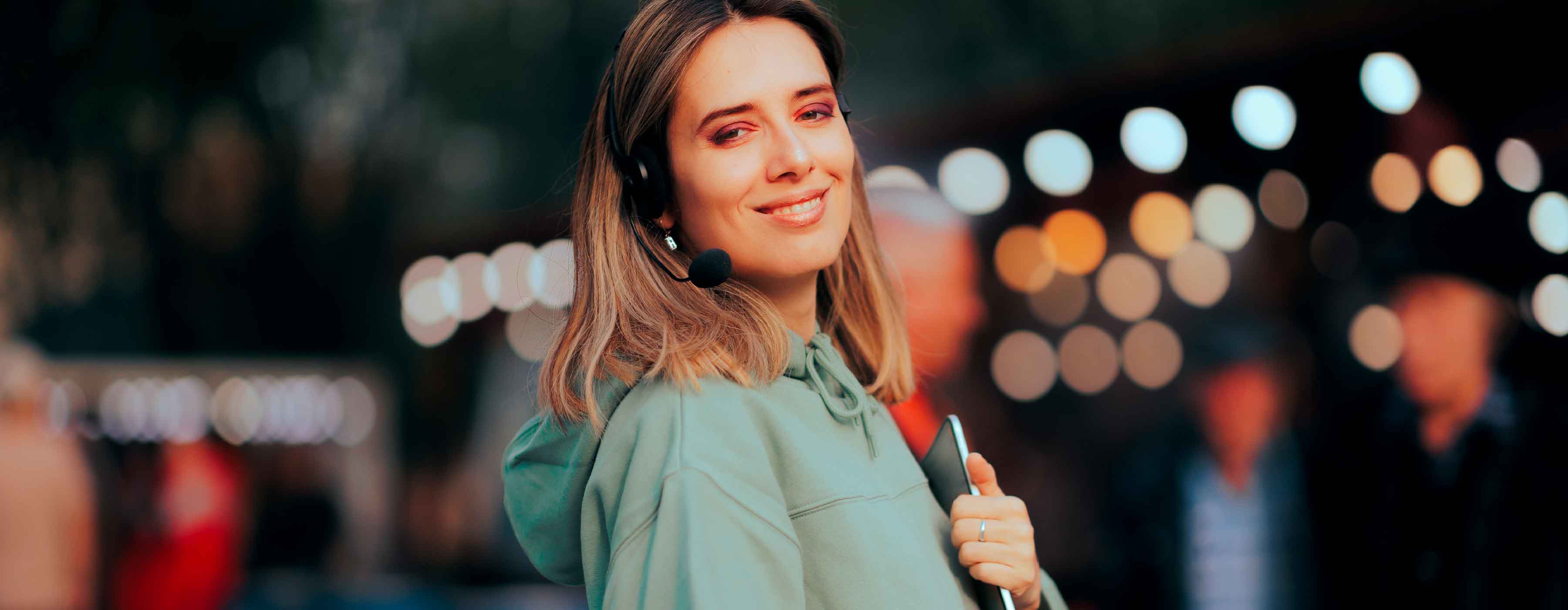 Produção Artística: concepção e planejamento - foto de mulher sorridente com headfone na cabeça segurando tablet.