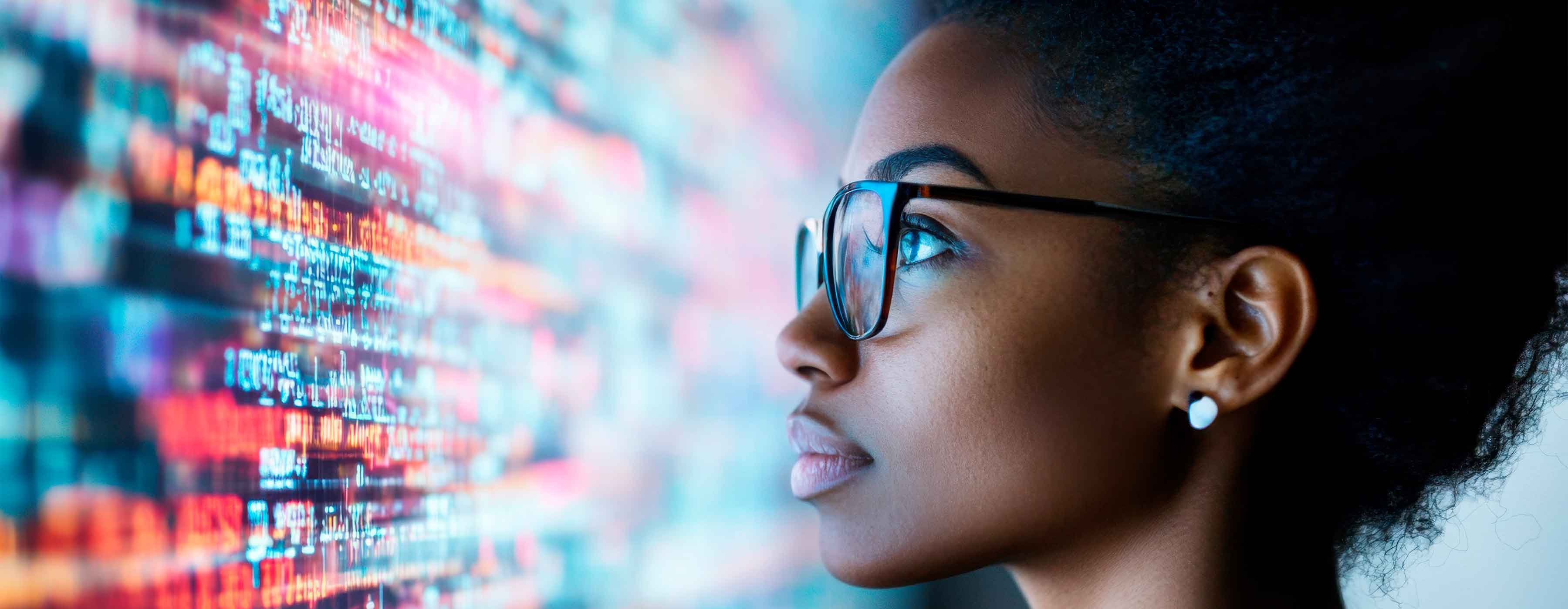 Técnicas de Machine Learning - foto do rosto de mulher olhando para códigos em uma grande tela.