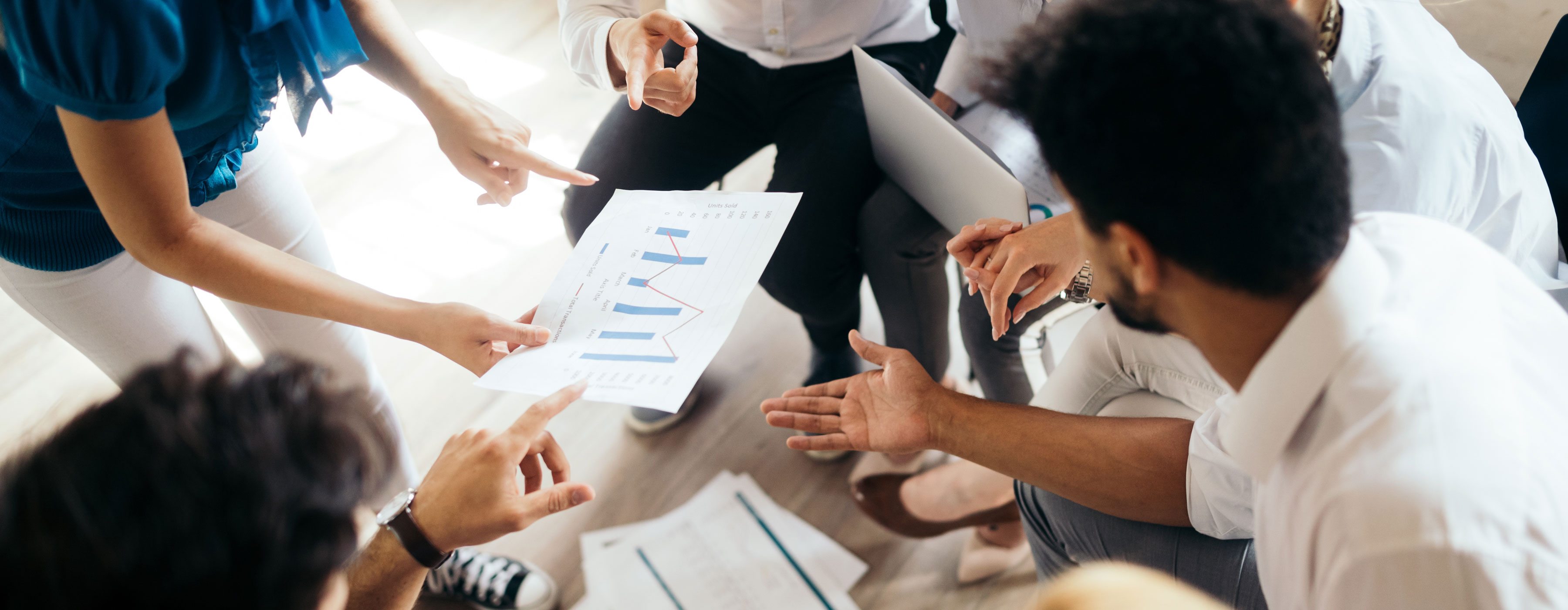 Design Thinking para Identificação e Validação de Oportunidades de Negócio - foto de um grupo de pessoas em círculo, com papéis e laptop nas mãos.