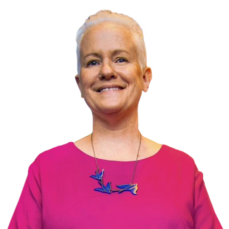 Foto de Ida Feldman sorrindo com uma blusa rosa e um colar de pássaros azuis.