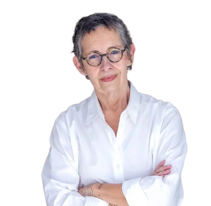 Foto de Pinky Wainer de braços cruzados, com óculos de grau e camisa branca.