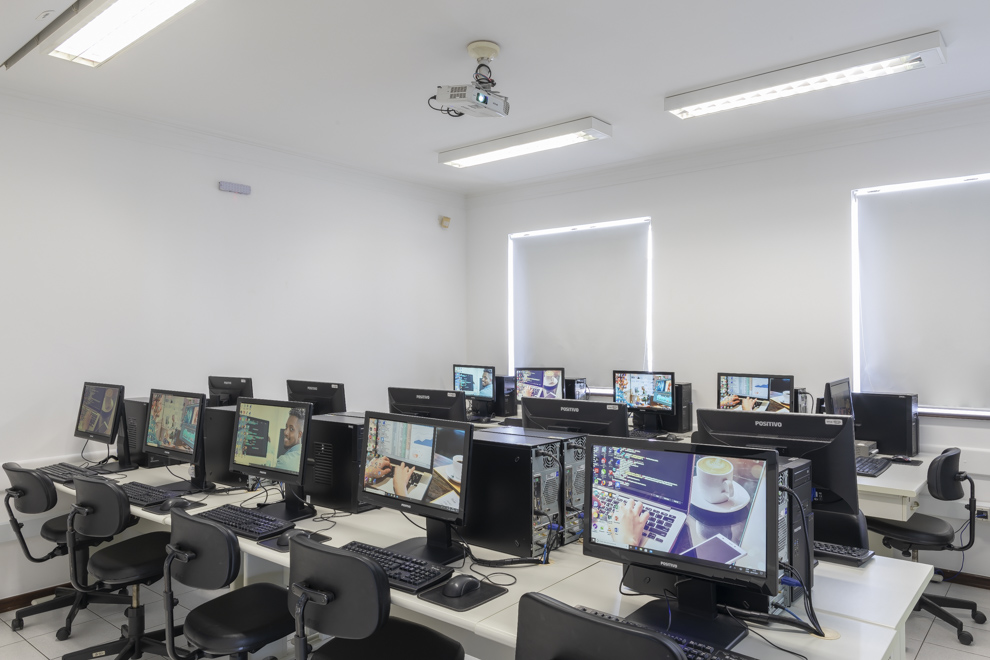 Laboratório de informática com diversos computadores enfileirados