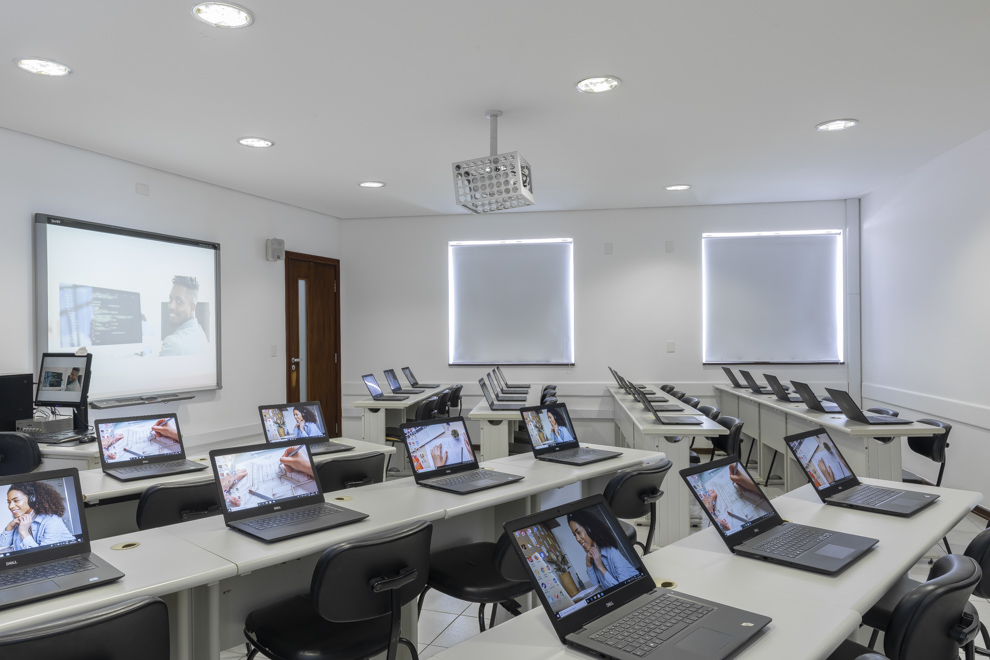 Sala de aula com mesas cadeiras, notebooks e retroprojetor