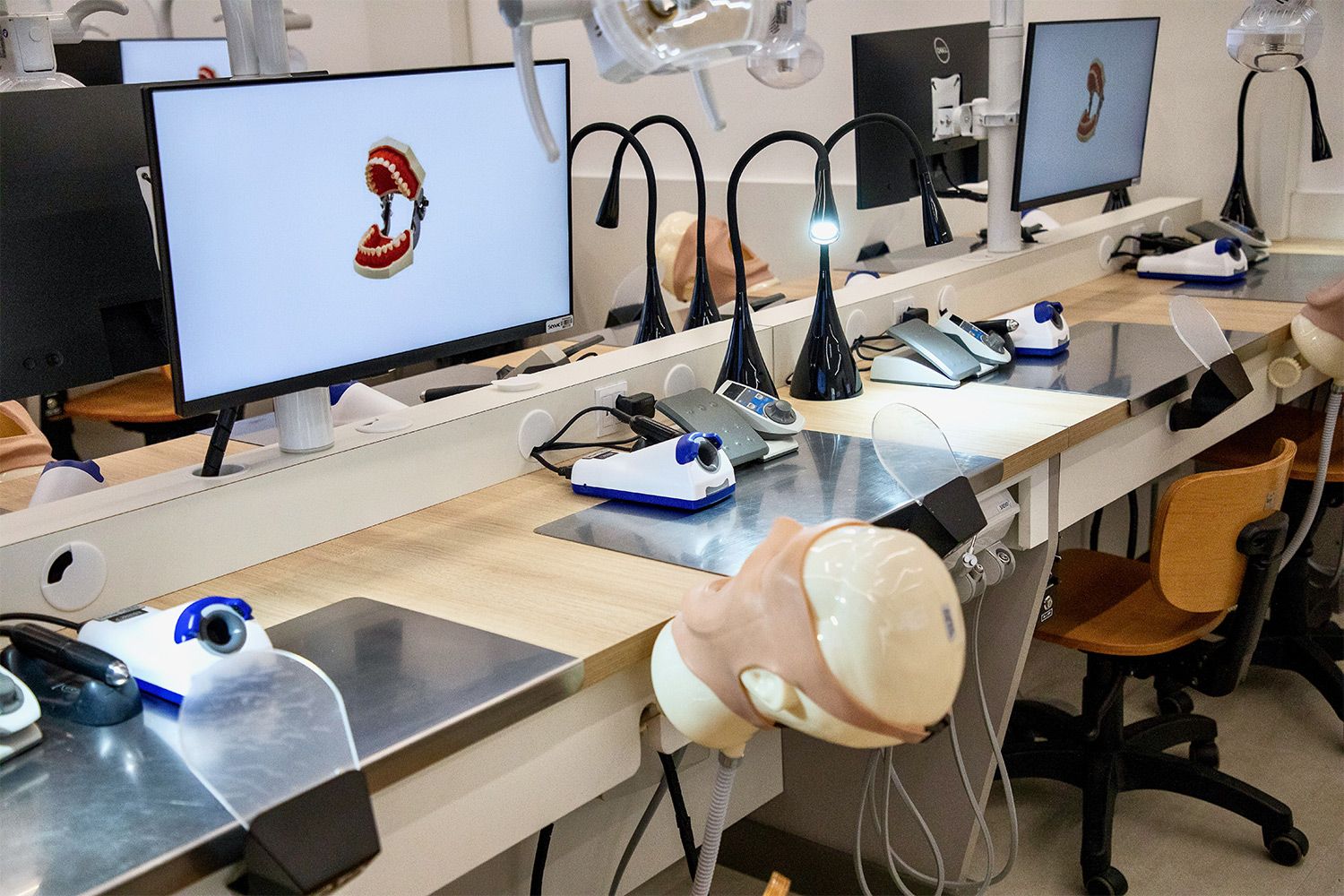 Imagem aproximada da bancada, equipamentos de digitalização odontológica, manequim e computador do laboratório.