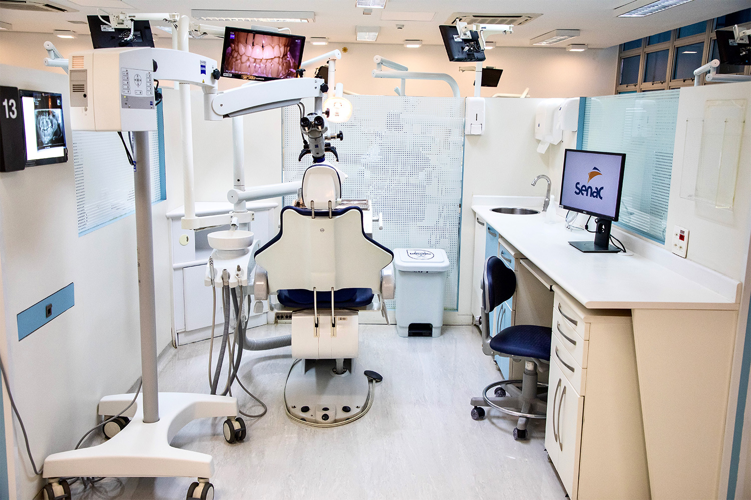Foto de equipamentos de atendimento e microscópio de alta magnificação na clínica odontológica.