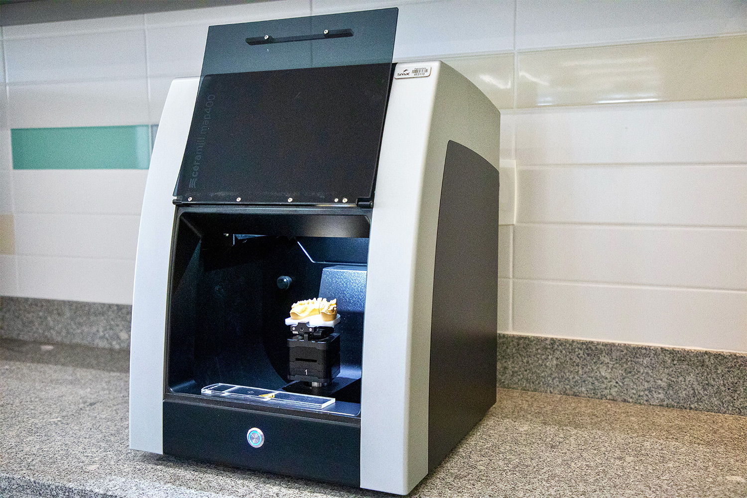 Foto de um scanner de bancada com uma prótese dentária dentro.