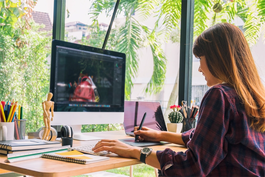 Imagem: técnica em design gráfico faz ajustes de desenho em mesa digitalizadora.