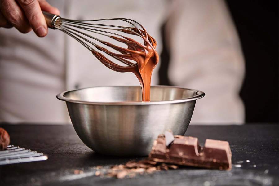Imagem: confeiteiro ajusta a temperatura do chocolate no processo chamado "temperagem" para ajustar a matéria-prima antes de iniciar o trabalho.