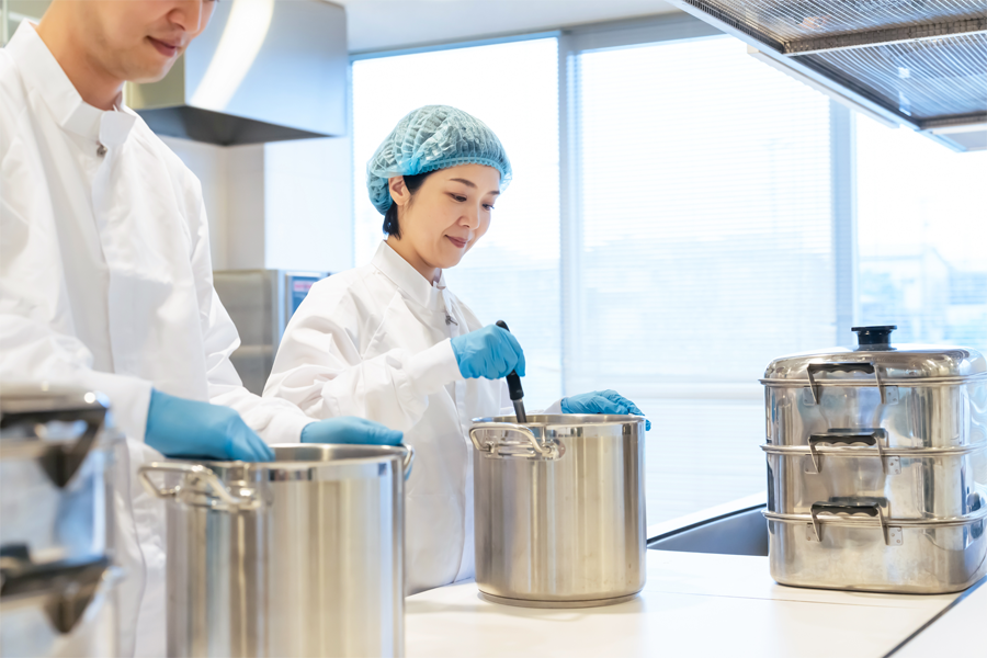 Imagem: técnica em nutrição e dietética observa a temperatura e a aparência do alimento a ser servido.